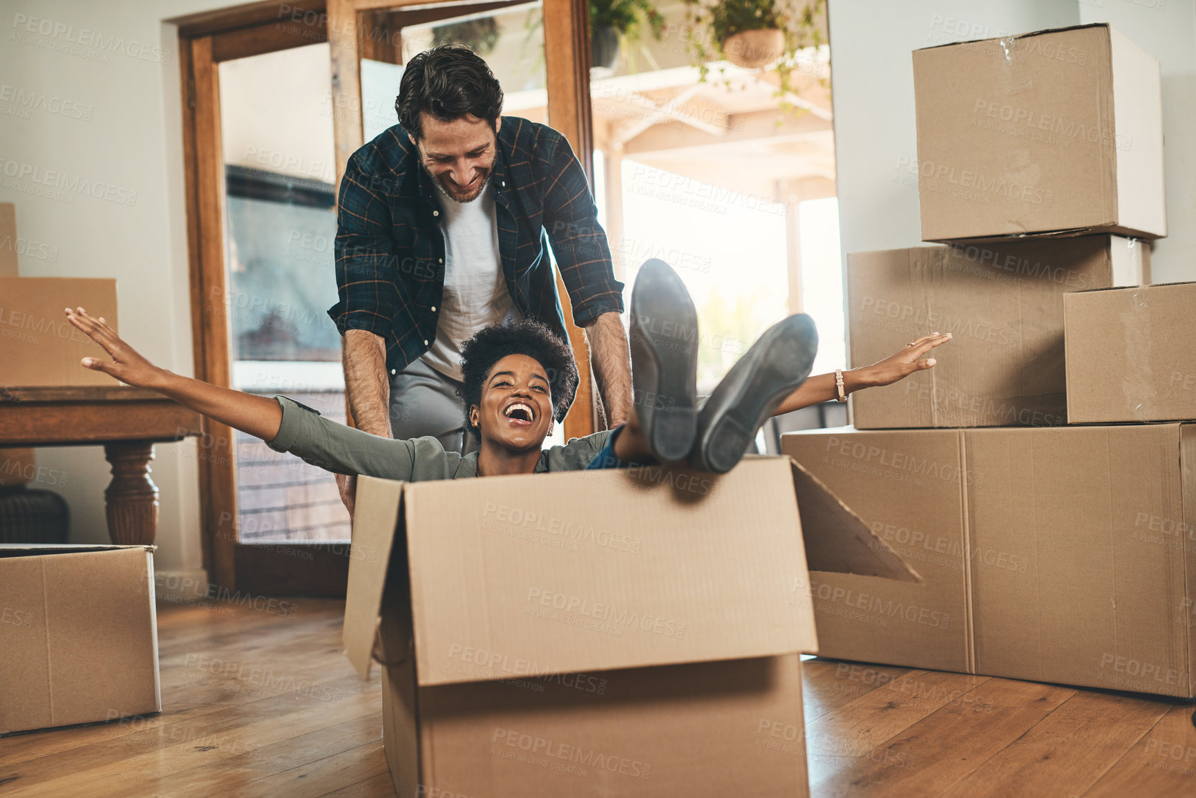 Buy stock photo Happy couple, box and real estate moving in house or property in renovation or investment together. Interracial man and woman playing in living room with boxes for relocation, celebration or new home