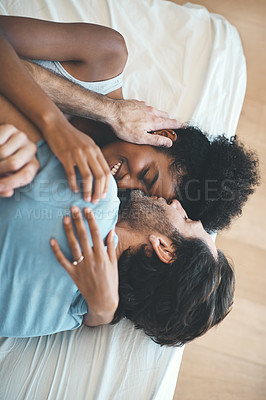 Buy stock photo High angle shot of an affectionate middle aged man kissing his wife on her forehead while lying on their bed at home