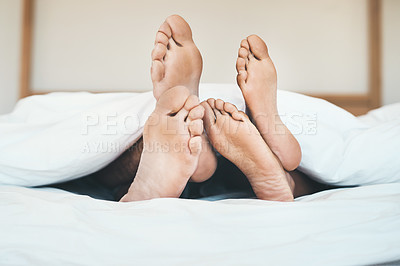 Buy stock photo Feet of an in love couple lying in bed, relaxing and bonding together at home. Closeup of a barefoot boyfriend and girlfriend sleeping, resting or taking a nap in their bedroom
