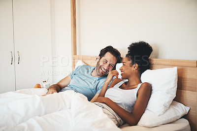 Buy stock photo Interracial couple, laughing and relax on bed for morning bonding, funny relationship or joke at home. Happy woman and man with smile, laugh and lying in bedroom for fun talk or conversation indoors