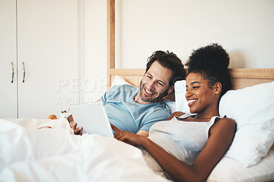 Buy stock photo Happy couple, tablet and relax on bed for morning entertainment or online streaming together at home. Interracial man and woman person relaxing in bedroom on technology for social media or browsing