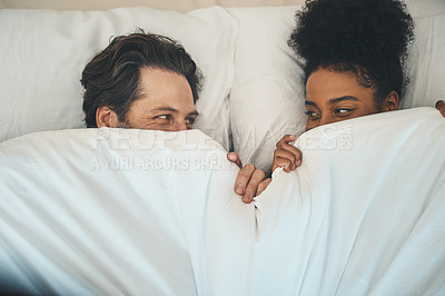 Buy stock photo Intimate, loving and affectionate couple or lovers in bed after a passionate night or sensual sex. Playful interracial partners having fun or hiding under blanket on a romantic honeymoon.