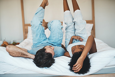 Buy stock photo Playful interracial couple bonding while lying on a bed in a bedroom in the morning. Loving, resting and relaxing diverse lovers enjoying quality time and being funny together in their broom at home