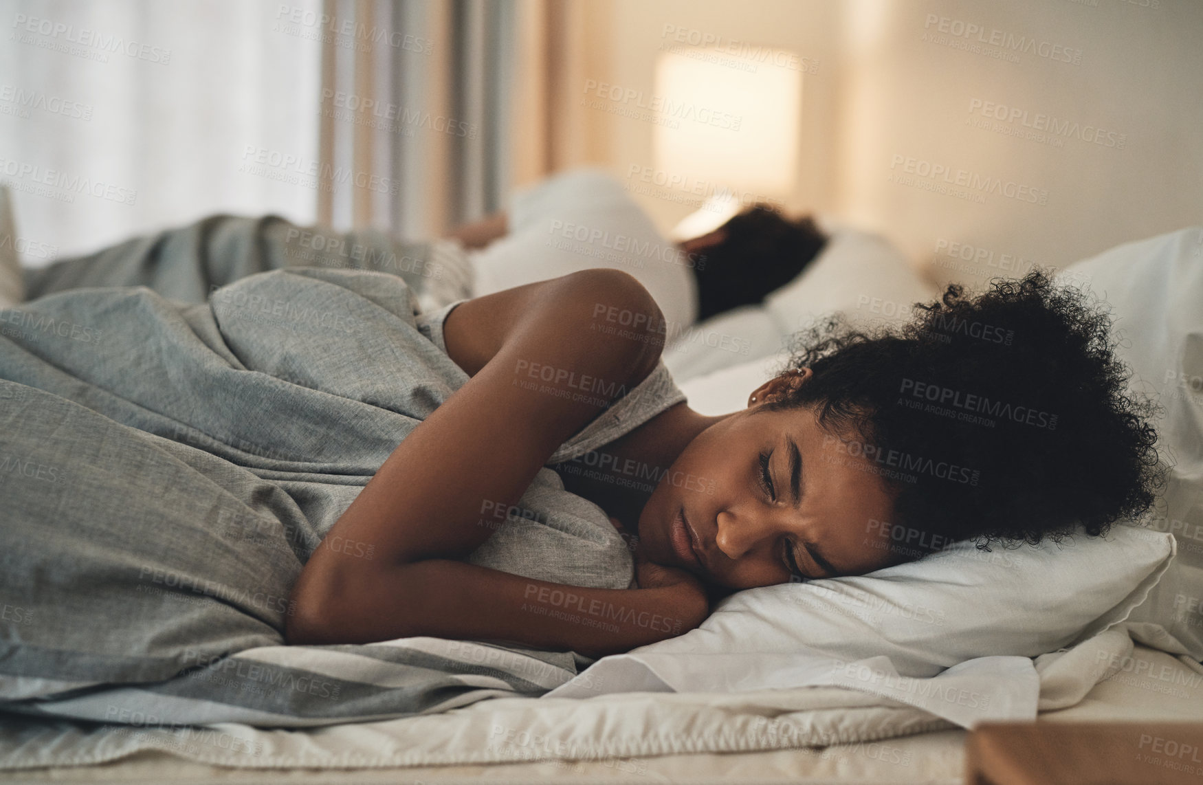Buy stock photo Cropped shot of an attractive young woman lying with her back turned on her husband after an argument in their bedroom