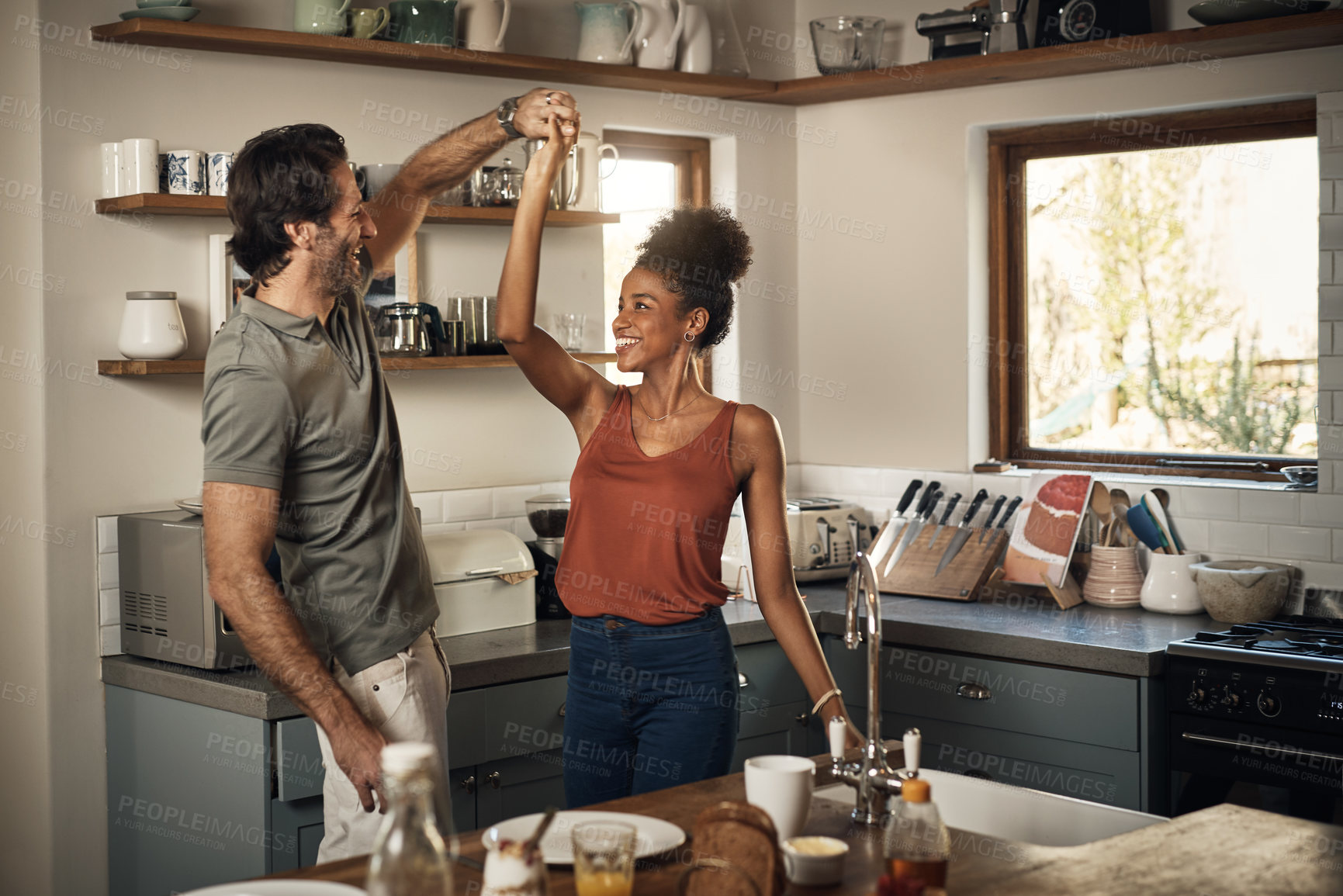 Buy stock photo Happy couple, dance and fun bonding in kitchen for romance, love or holiday together at home. Interracial man and woman dancing in happiness for romantic relationship or enjoying weekend in the house
