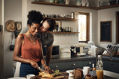 Buy stock photo Interracial couple, kiss and cooking in kitchen for morning breakfast, love or caring relationship at home. Man kissing woman while making food, romantic meal or cutting ingredients on table in house