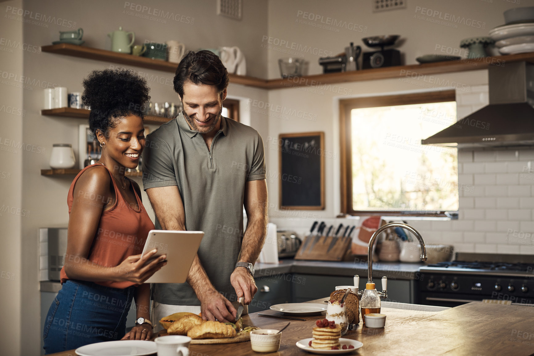 Buy stock photo Happy, smiling and cheerful couple cooking and browsing digital tablet while bonding together at home. Man cutting vegetables and wife reads online recipe while preparing a healthy meal together