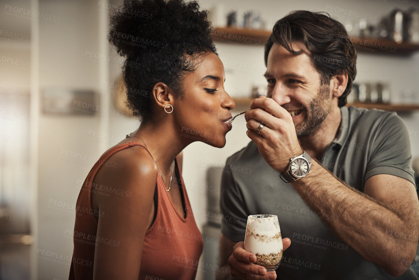 Buy stock photo Cropped shot of an affectionate middle aged man feeding his wife dessert in their kitchen at home