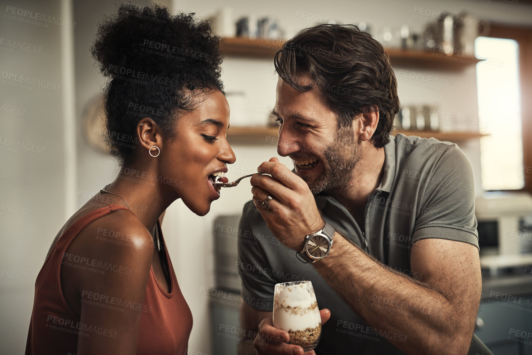 Buy stock photo Cropped shot of an affectionate middle aged man feeding his wife dessert in their kitchen at home