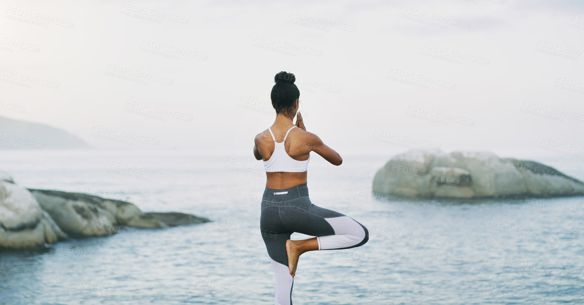 Buy stock photo Beach, yoga or woman with balance, leg or body flexibility for peace or mindfulness in outdoor nature to relax. Chakra, calm or back view of girl on rock at sea or ocean for prayer pose in pilates