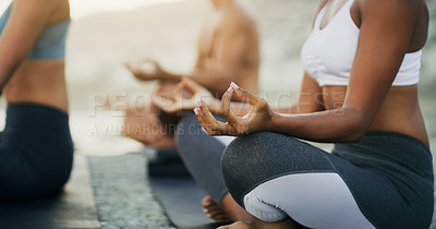 Buy stock photo Cropped shot of an unrecognizable group of people sitting and meditating together while on the beach during an overcast day