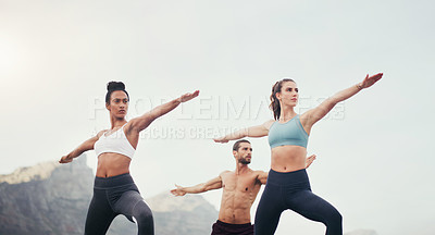 Buy stock photo Cropped shot of three young people standing in a warrior position while doing yoga on the beach