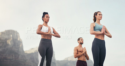 Buy stock photo Cropped shot of a group of young people standing and meditating together while on the beach during an overcast day