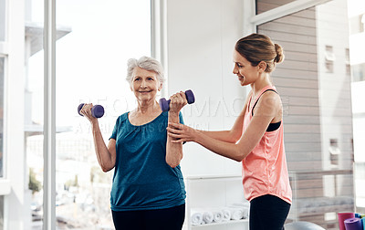 Buy stock photo Shot of a fitness instructor helping a senior woman with some weightlifting exercises