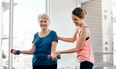 Buy stock photo Shot of a fitness instructor helping a senior woman with some weightlifting exercises