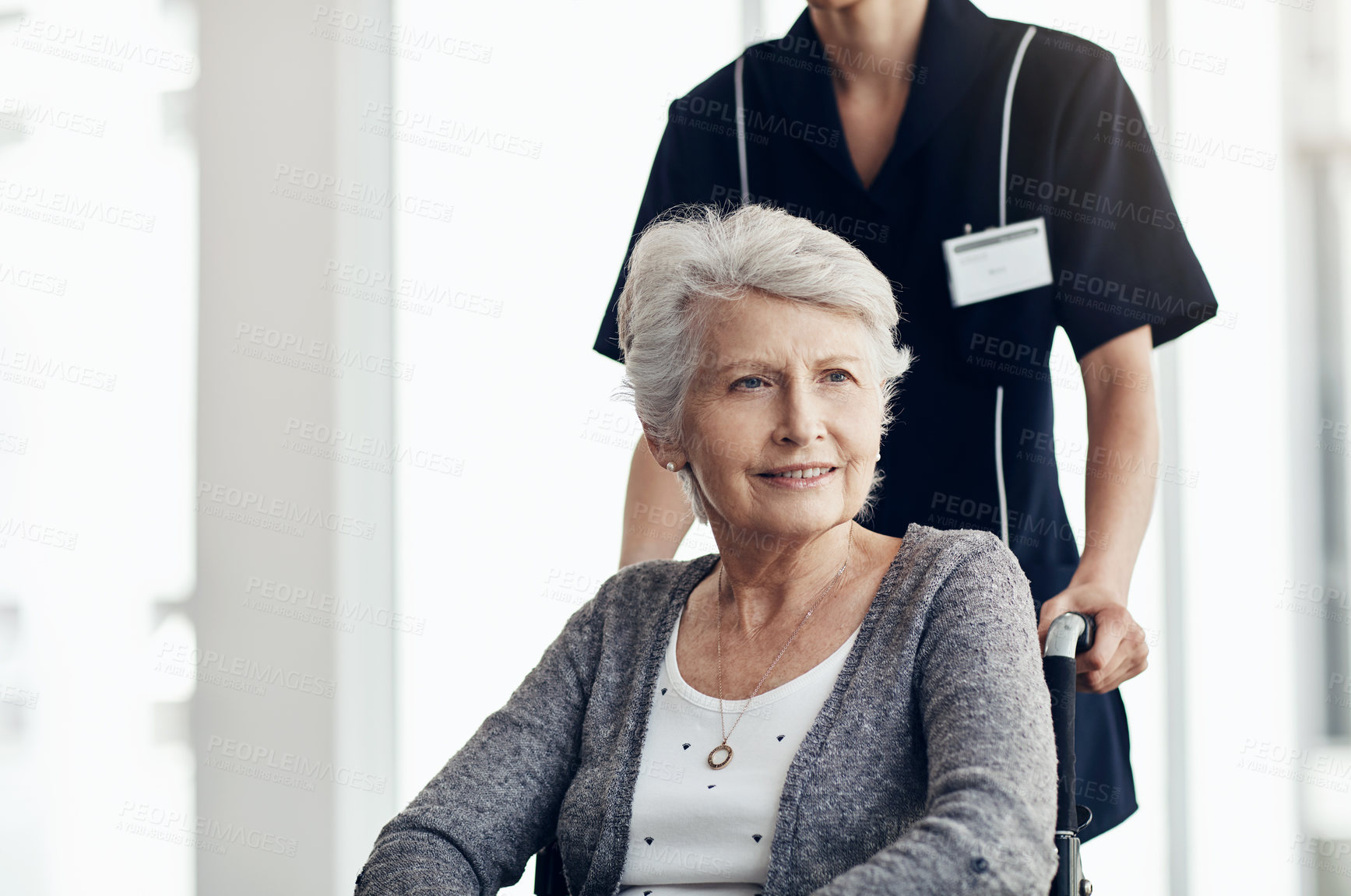 Buy stock photo Shot of a senior woman in a wheelchair being pushed by a female nurse