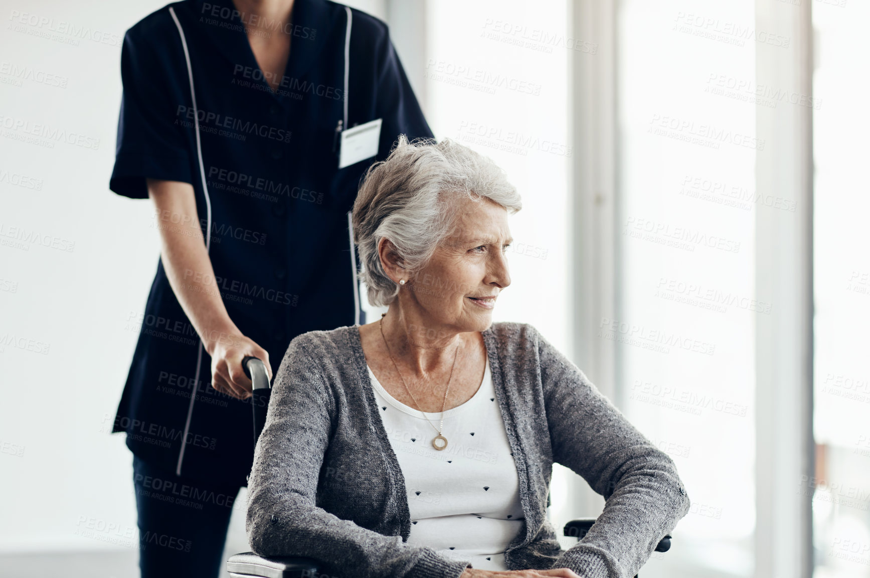 Buy stock photo Shot of a senior woman in a wheelchair being pushed by a female nurse