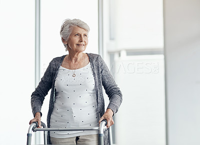 Buy stock photo Shot of a senior woman walking with the assistance of a walker