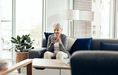 Buy stock photo Shot of a senior woman enjoying a cup of coffee while relaxing at home