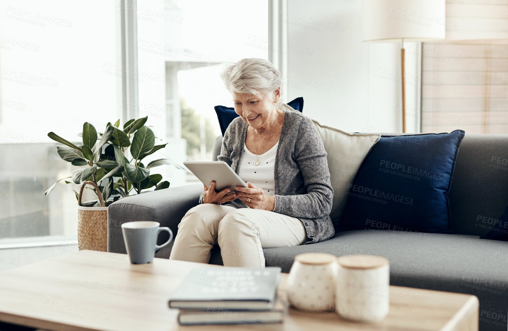 Buy stock photo Senior woman, tablet and home with digital, game app or social media scroll for news in retirement. Lounge, sofa and smile with web, tech and relax in living room with series streaming at morning