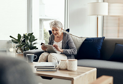 Buy stock photo Shot of a senior woman holding her credit card while browsing on a digital tablet