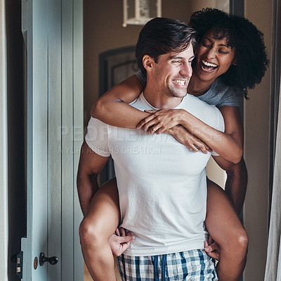 Buy stock photo Shot of a young man carrying his girlfriend piggy back while spending some time together at home