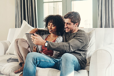 Buy stock photo Couple, bonding and tablet with streaming, watching movie and happy in lounge, sofa and home on break. Woman, man and technology as interracial partner in together, cheerful and embrace in connection