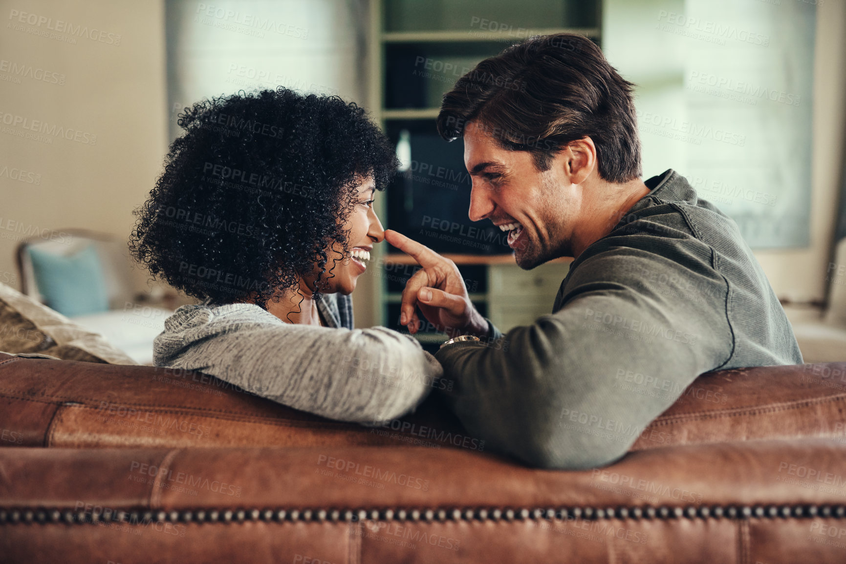 Buy stock photo Interracial couple, love and laughing on couch in morning for care, support and together in apartment. Happy, man and woman on sofa in home for date and trust for relax in living room on weekend