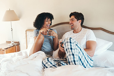 Buy stock photo Shot of an affectionate young couple drinking coffee and spending time together in bed at home