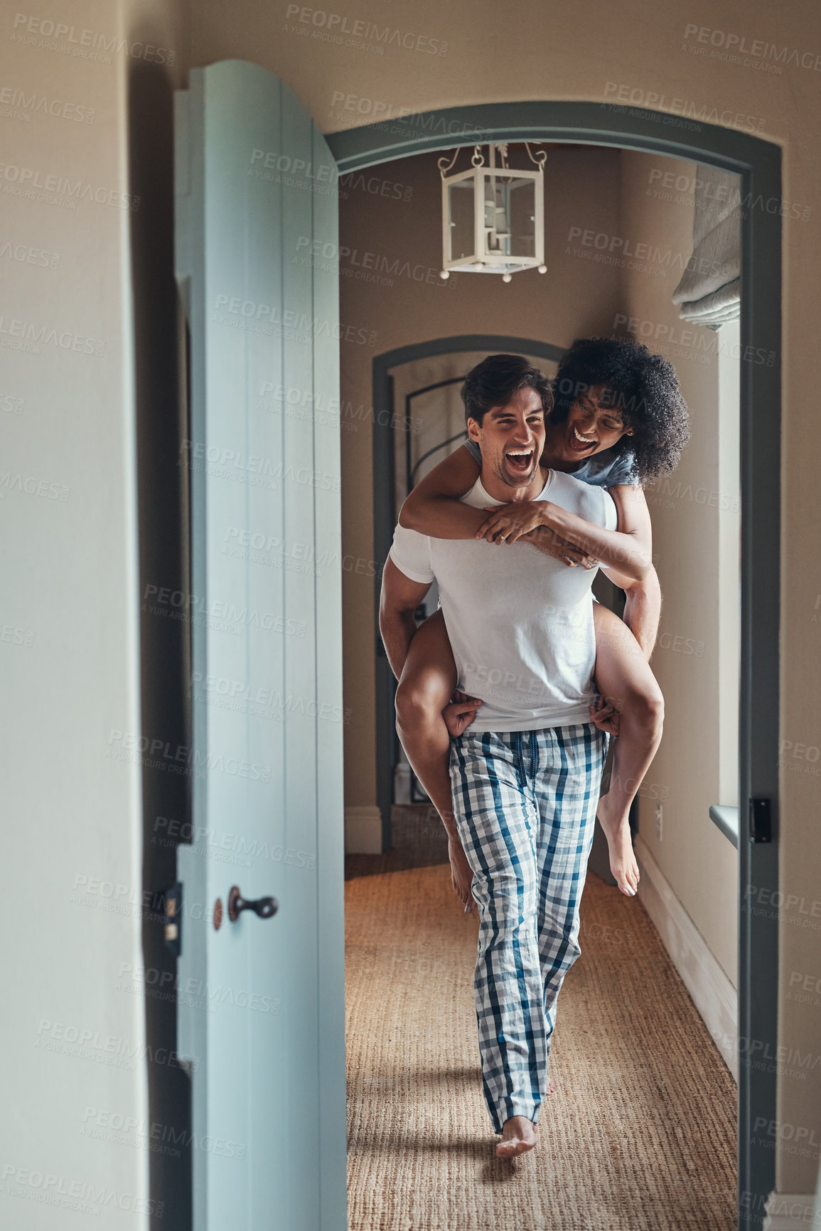 Buy stock photo Full length shot of a young man carrying his girlfriend piggy back while spending some time together at home