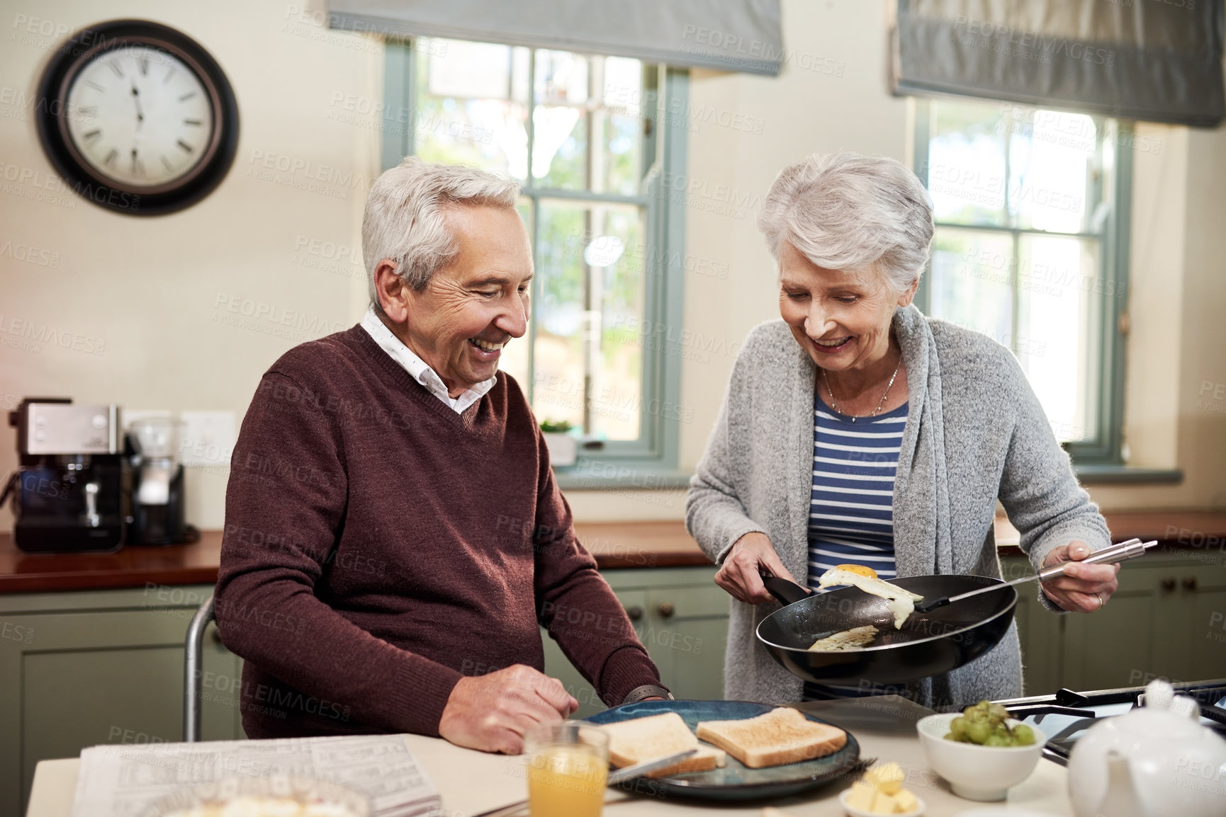 Buy stock photo Shot of an affectionate senior couple cooking together in their kitchen at home