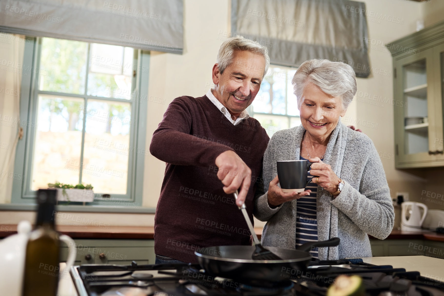 Buy stock photo Shot of an affectionate senior couple cooking together in their kitchen at home