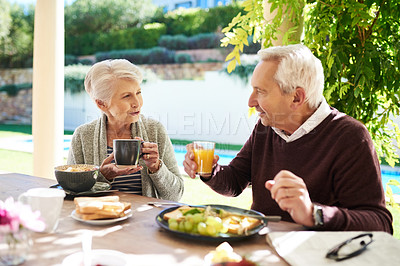Buy stock photo Shot of an affectionate senior couple enjoying a meal together outdoors
