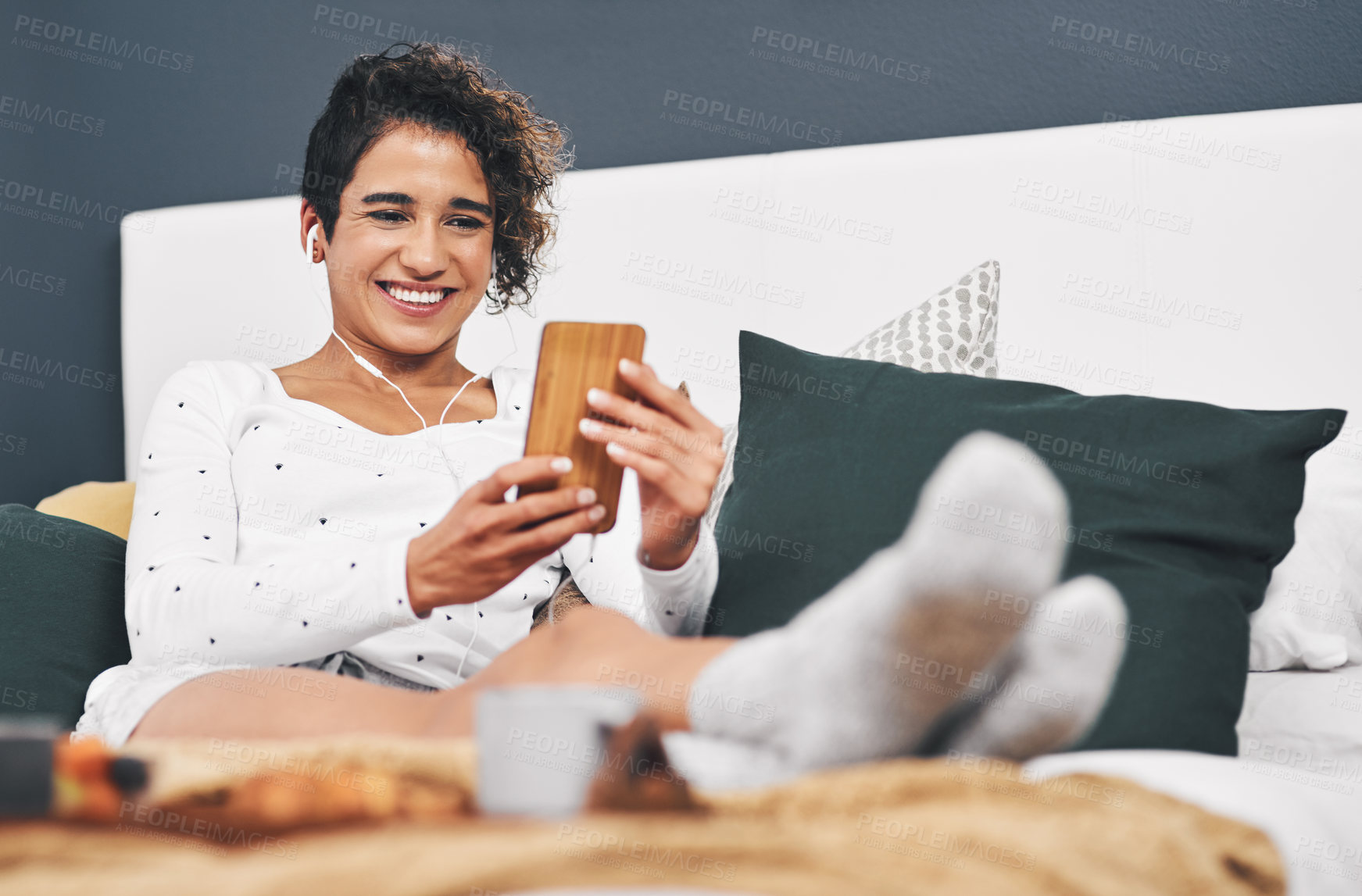 Buy stock photo Full length shot of an attractive young woman sitting on her bed and using her cellphone while at home