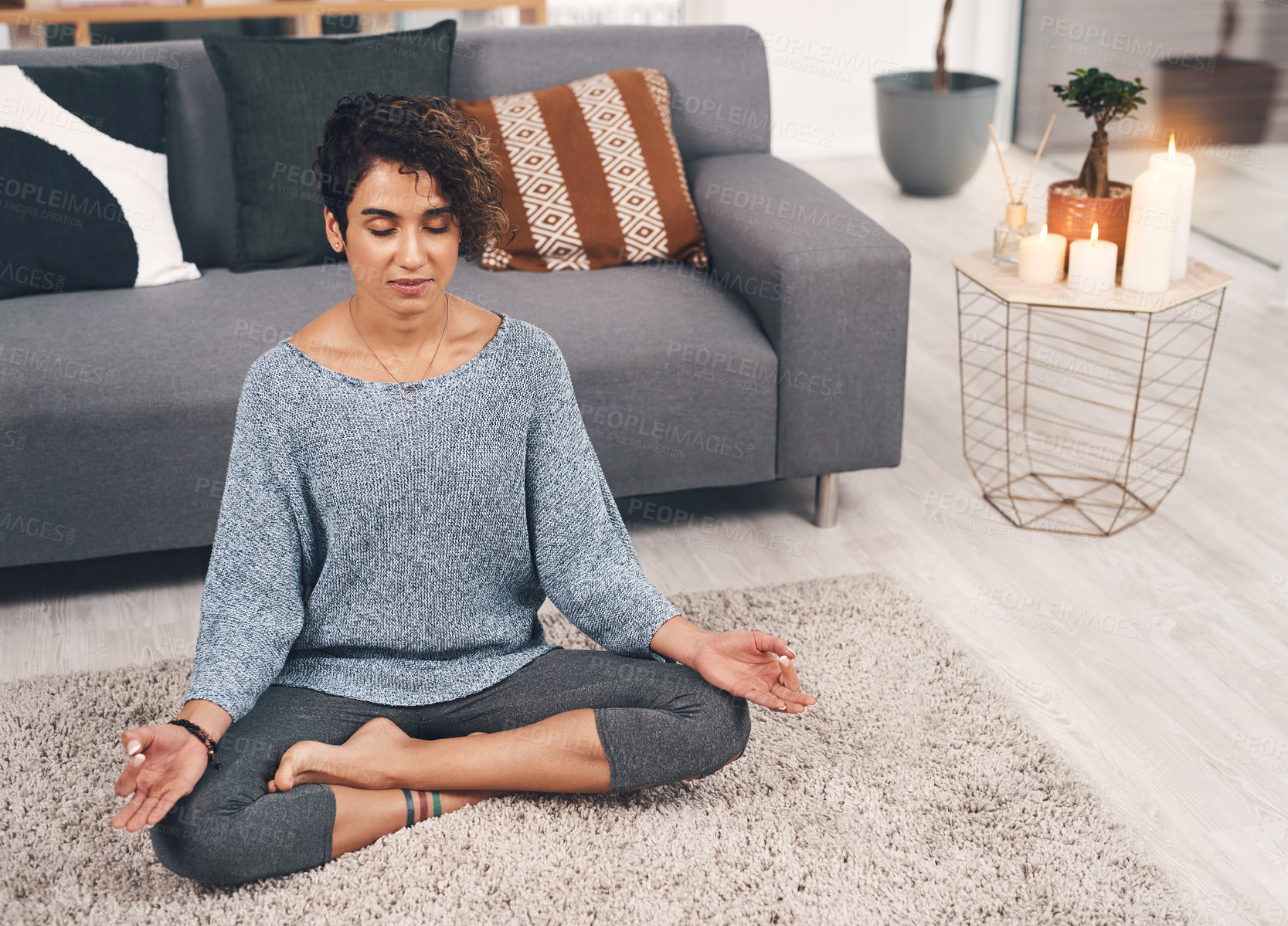 Buy stock photo Full length shot of an attractive young woman sitting and meditating in her lounge while at home