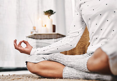 Buy stock photo Cropped shot of an unrecognizable woman sitting in a lotus position alone and meditating in her bedroom at home
