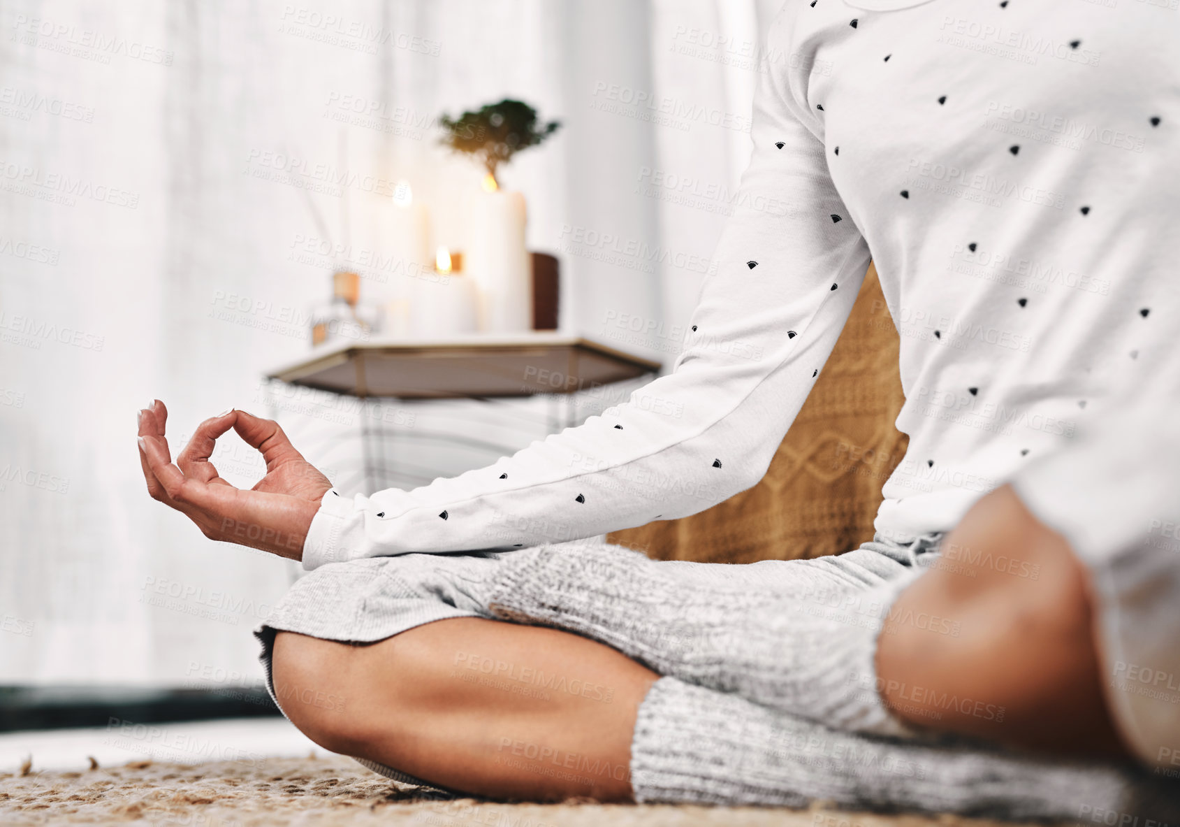 Buy stock photo Cropped shot of an unrecognizable woman sitting in a lotus position alone and meditating in her bedroom at home