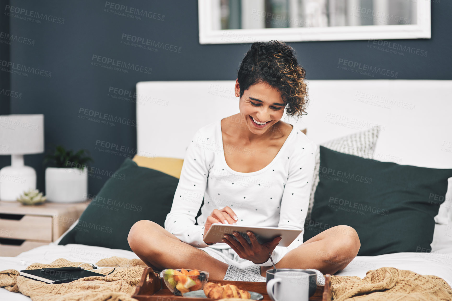 Buy stock photo Full length shot of an attractive young woman sitting on her bed and using her tablet while at home