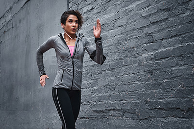 Buy stock photo Cropped shot of an attractive young woman wearing earphones and workout clothes while running outside