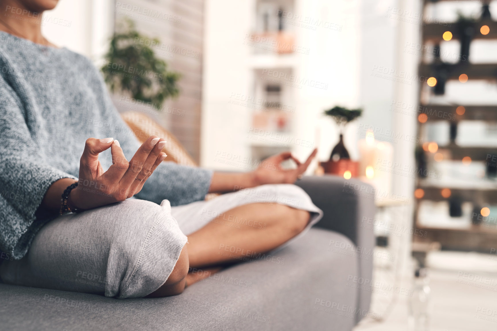 Buy stock photo Cropped shot of an unrecognizable woman sitting in a lotus position alone and meditating in her living room at home