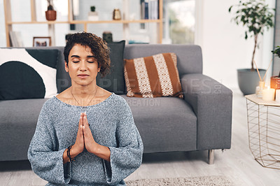 Buy stock photo Cropped shot of an attractive young woman sitting and meditating in her living room at home