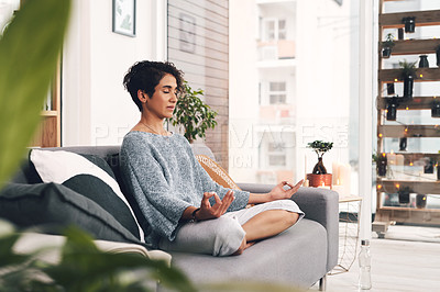 Buy stock photo Full length shot of an attractive young woman sitting and meditating on her sofa in the living room at home