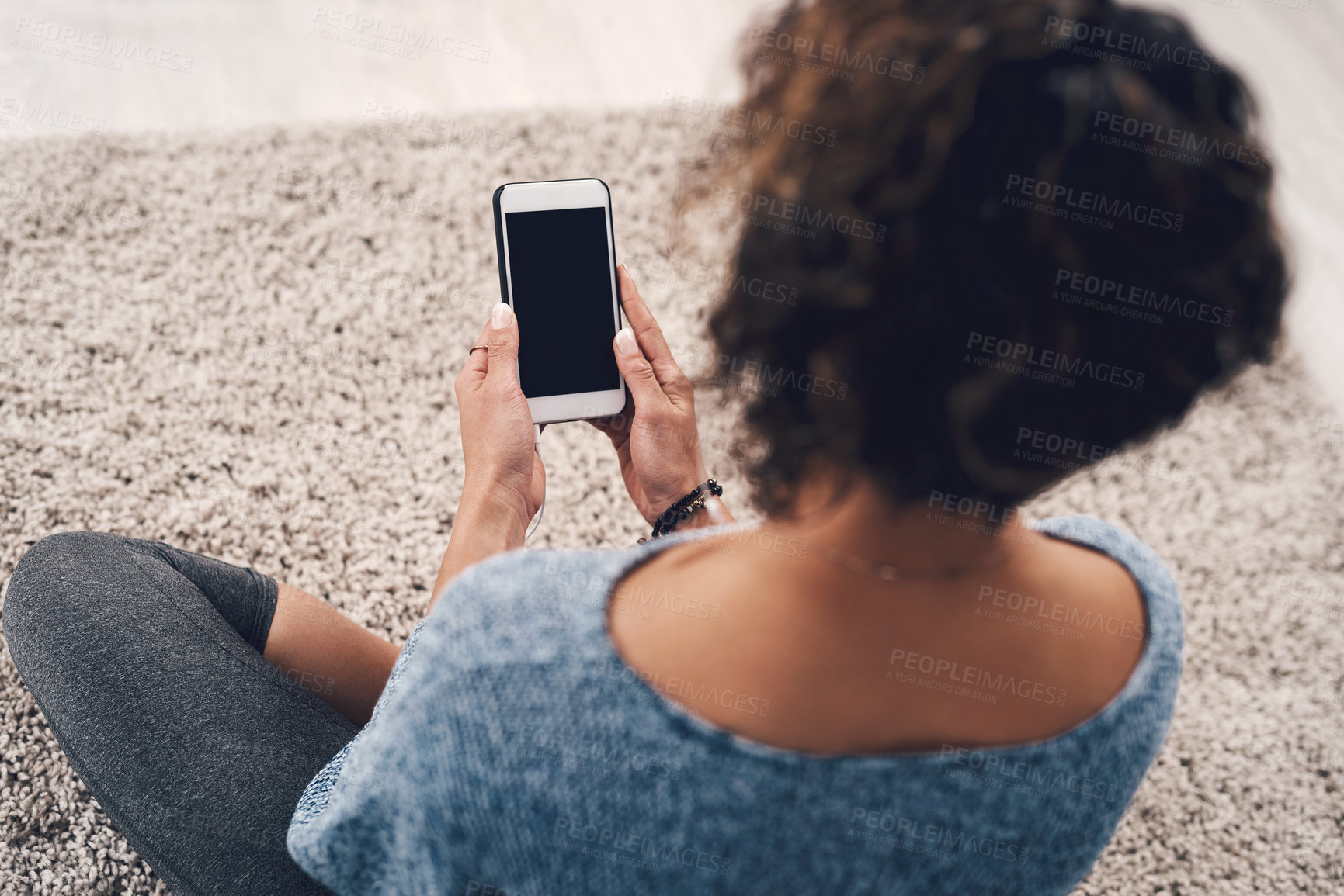 Buy stock photo Rearview shot of an unrecognizable woman using her cellphone while sitting in her living room at home