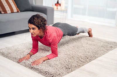 Buy stock photo Full length shot of an attractive young woman exercising and holding a plank while in her living room at home