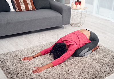 Buy stock photo Full length shot of an unrecognizable woman holding a child's pose while doing yoga in her living room at home