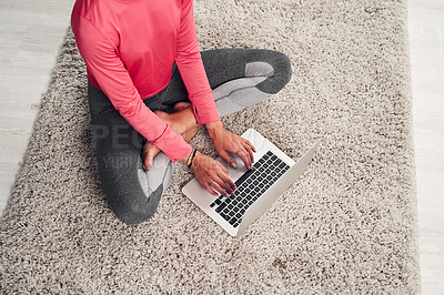Buy stock photo Cropped shot of an unrecognizable woman sitting and using a laptop in her living room at home