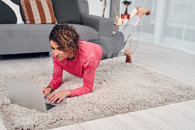 Buy stock photo Full length shot of an attractive young woman multitasking and doing pilates while using a laptop in the living room
