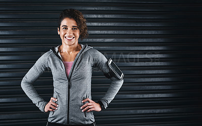 Buy stock photo Cropped portrait of an attractive young woman standing with her arms akimbo against a black background before her workout
