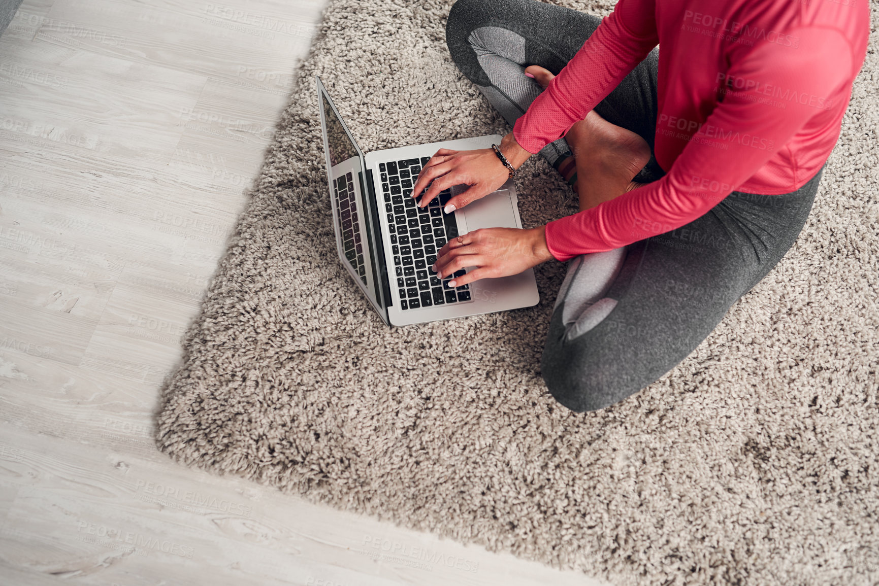 Buy stock photo Cropped shot of an unrecognizable woman sitting and using a laptop in her living room at home