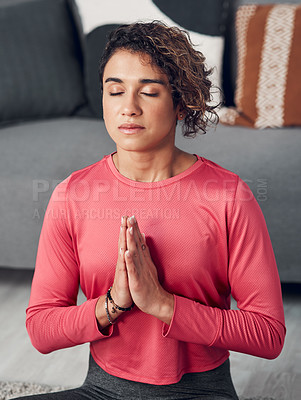 Buy stock photo Cropped shot of an attractive young woman sitting and meditating in her living room at home